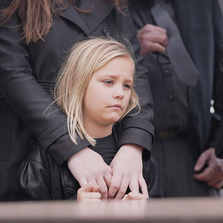 child standing with adults at a funeral