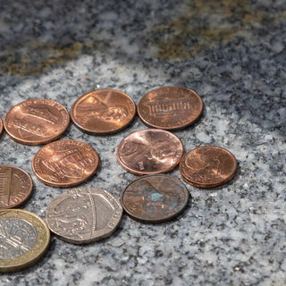 pennies and other coins on top of a headstone