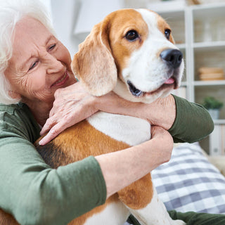 woman smiling while embracing her Beagle dog