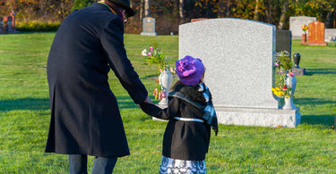 Granddaughter and grandfather walking through grass in a cemetery 