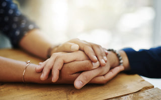 close up of two people's hands being held on a table