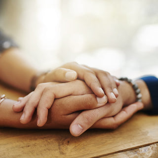 close up of two people's hands being held on a table