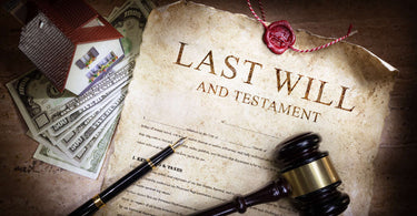 a Last Will and Testament document on a table next to a gable, money, a house trinket and necklace