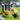 little boy in a yellow rain coat crouching in front of a headstone with flowers in front of it