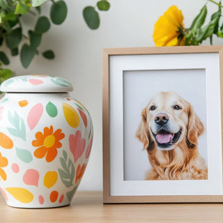 Floral decorated pet urn sits next to a framed photo of a golden retriever