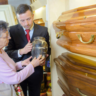 woman being shown an urn while in front of a coffin wall display