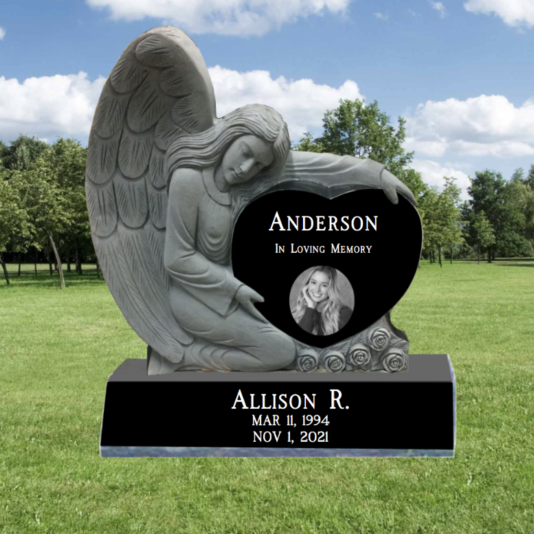 Carved Angel hugging a Single Black Granite Heart Headstone. In the heart is a last name, and the words 