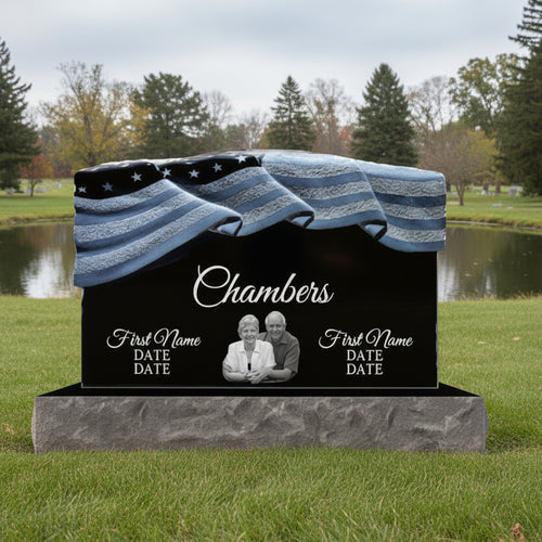 A black granite headstone with a patriotic design featuring the American flag, and spaces for personalization such as name and date.